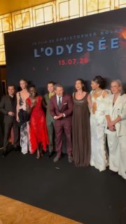 Групповая фотография на премьере фильма на фоне постера «L'ODYSSEE»: несколько гостей и организаторы у сцены во время события в Париже.