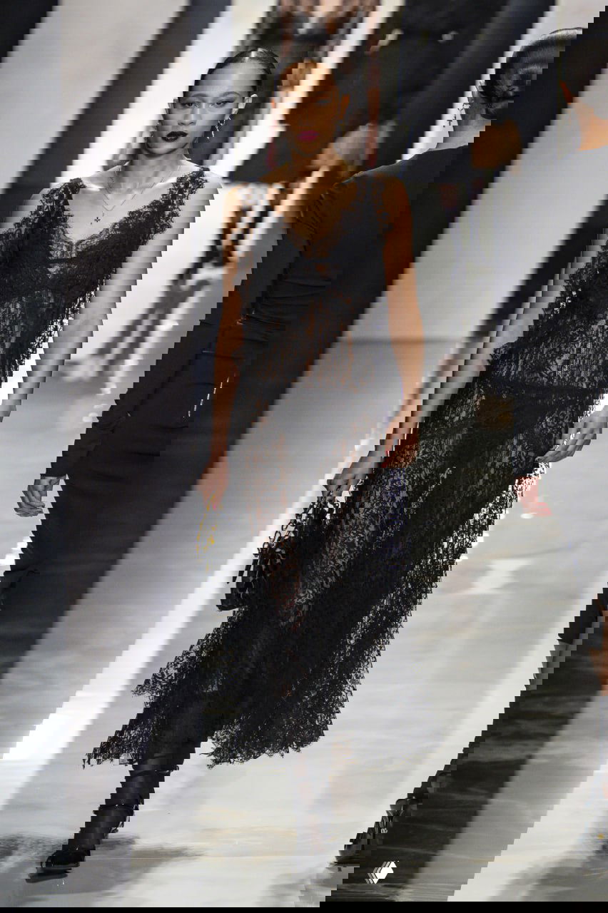 Модель в прозрачном чёрном кружевном платье с яркой красной помадой представляет вечерний образ на показе Dolce & Gabbana.