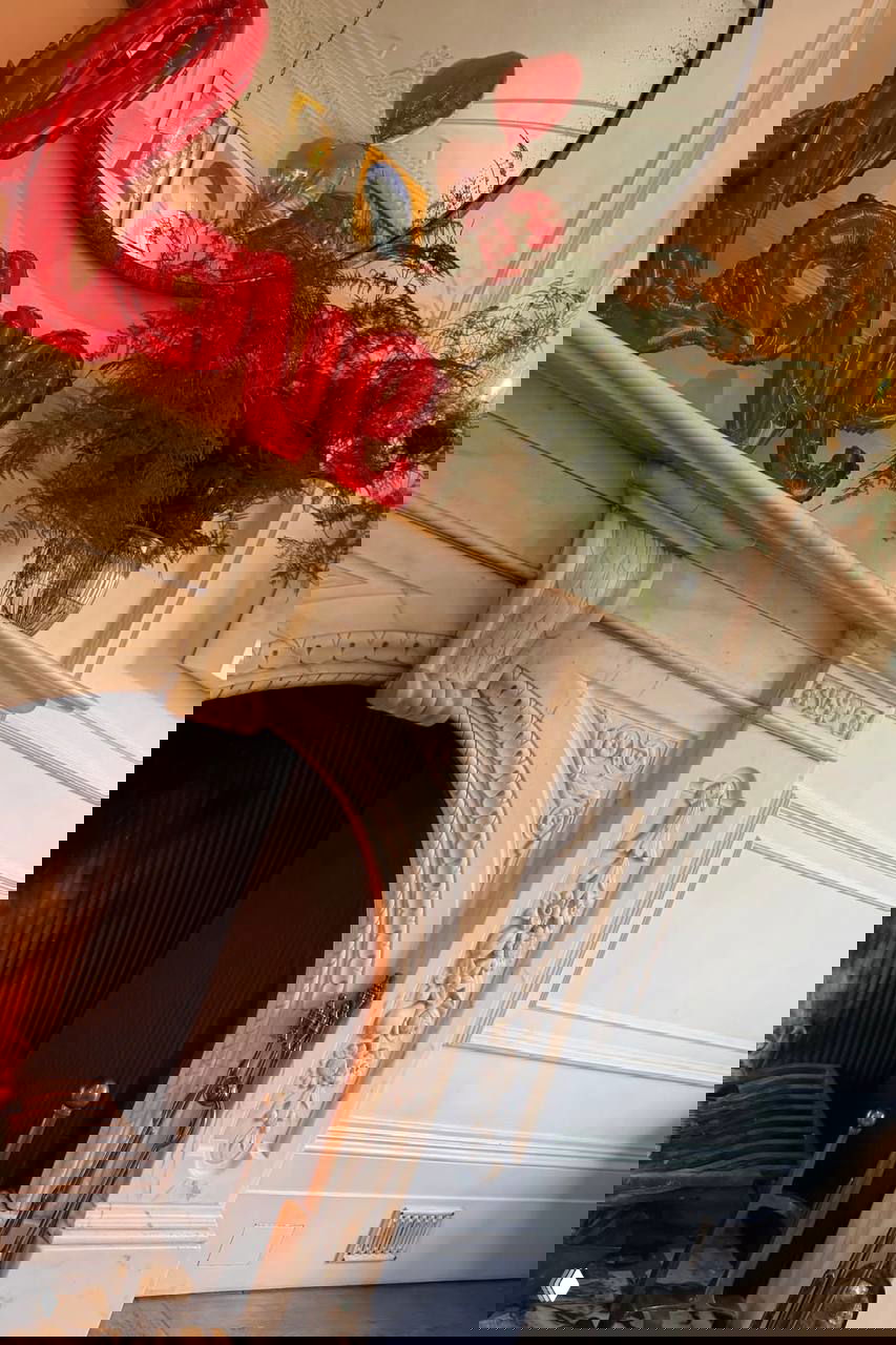 Камин с праздничным декором: фольгированные красные буквы «love», зелёные растения и зеркальное отражение — интерьер для романтического утра.