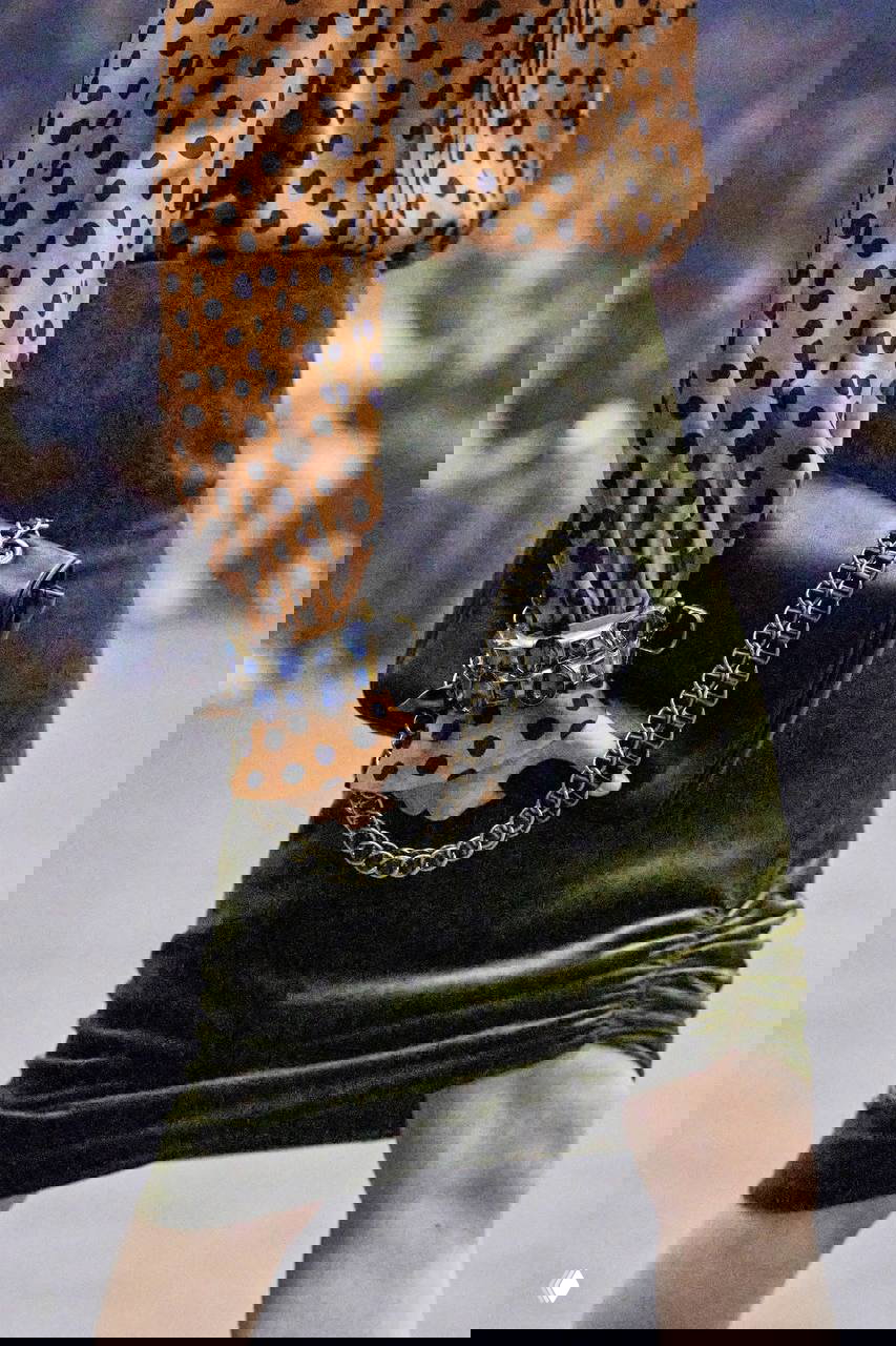 Крупный план запястья и браслета с крупными синими камнями и цепочкой сумки — пример комбинирования драгоценных оттенков и тяжёлой фурнитуры.