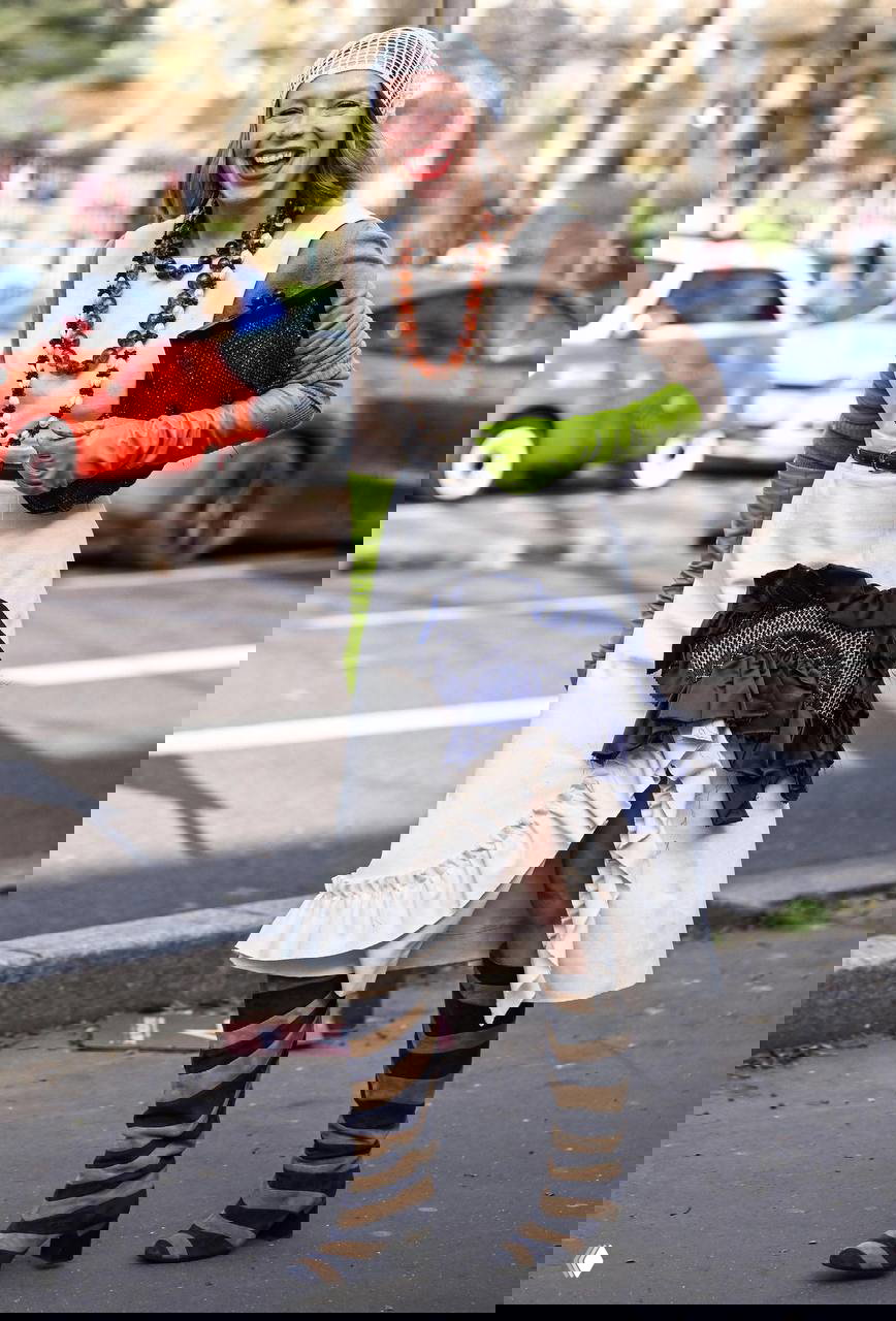 Уличный образ с многослойным платьем, зелеными длинными перчатками и крупными украшениями — эклектичный гибрид старого глянца и современного стайлинга.