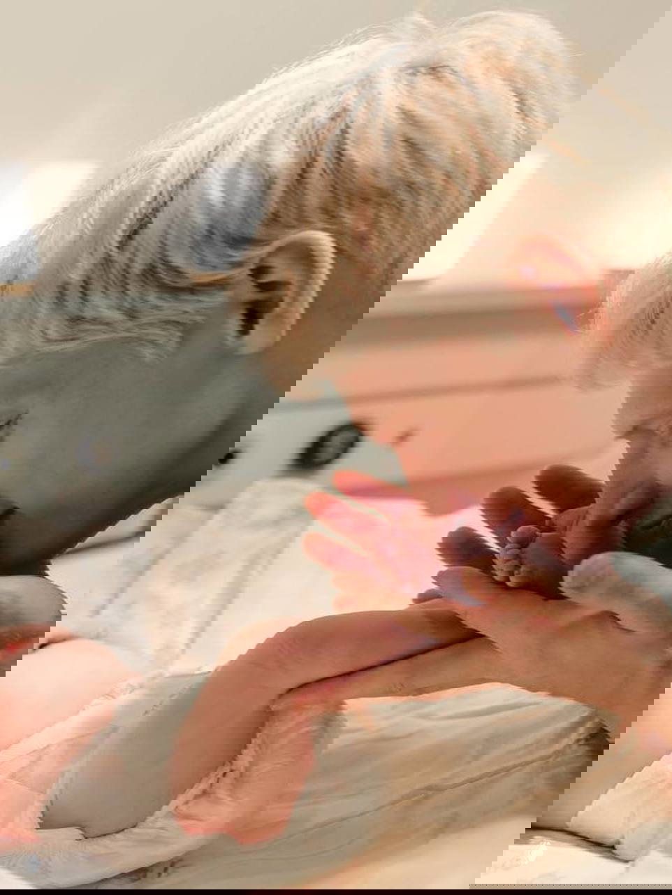 Святослав Рогожан нежно целует ножку новорождённого: крупный план отца и малыша в теплой атмосфере родильного зала.