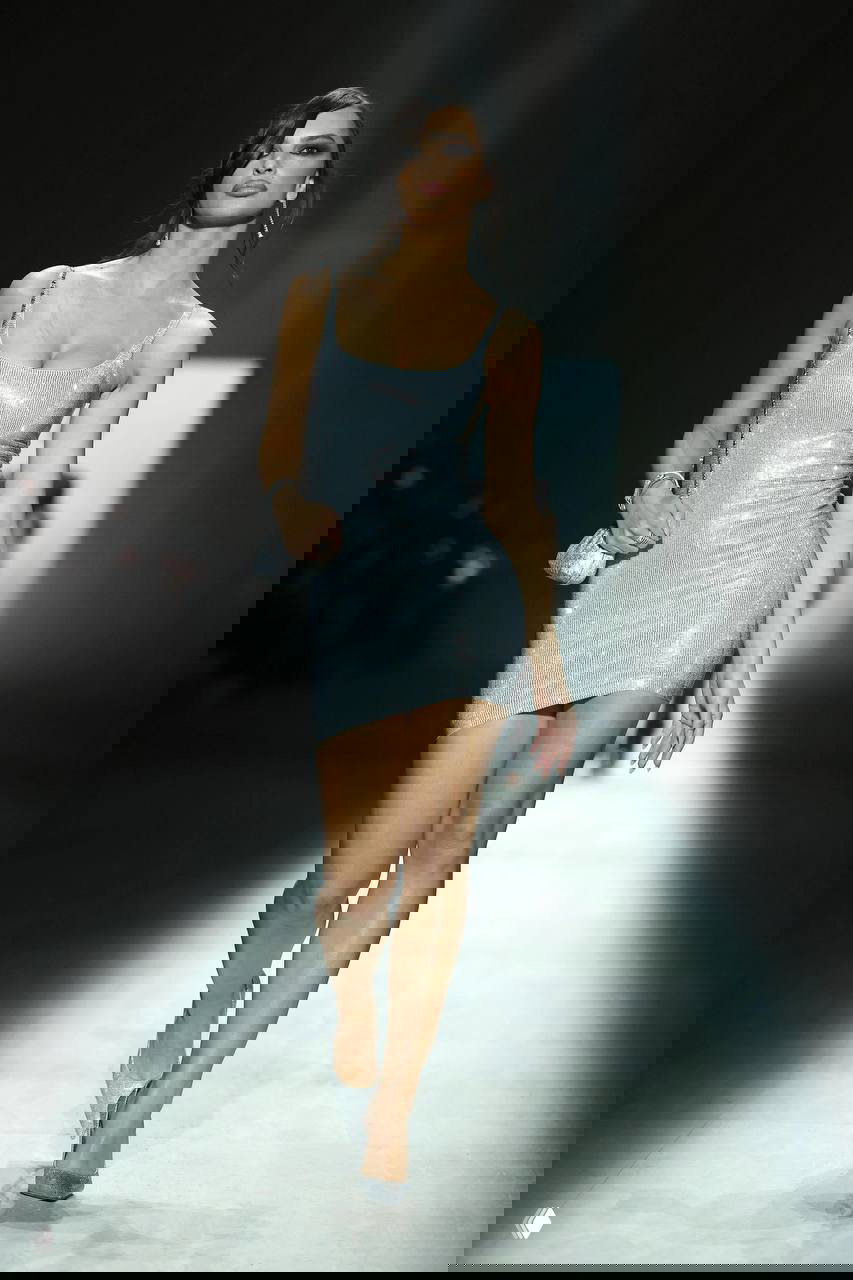 Модель в коротком блестящем платье на подиуме, минималистичный силует с ярким глянцевым эффектом ткани — возвращение гламура и сексуальности в коллекциях.