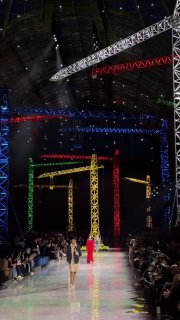 Общий вид подиума Chanel в Гран‑Пале: зеркальный пол, разноцветные освещенные краны и модели, идущие по длинной дорожке в индустриальной обстановке.
