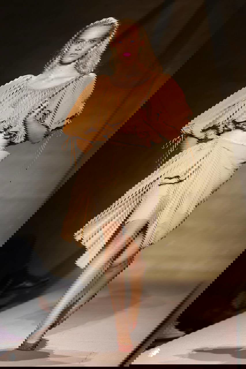 Легкий бохо-образ: объемный топ карамельного оттенка и драпированная юбка на подиуме с теплым светом и минимальным фоном.