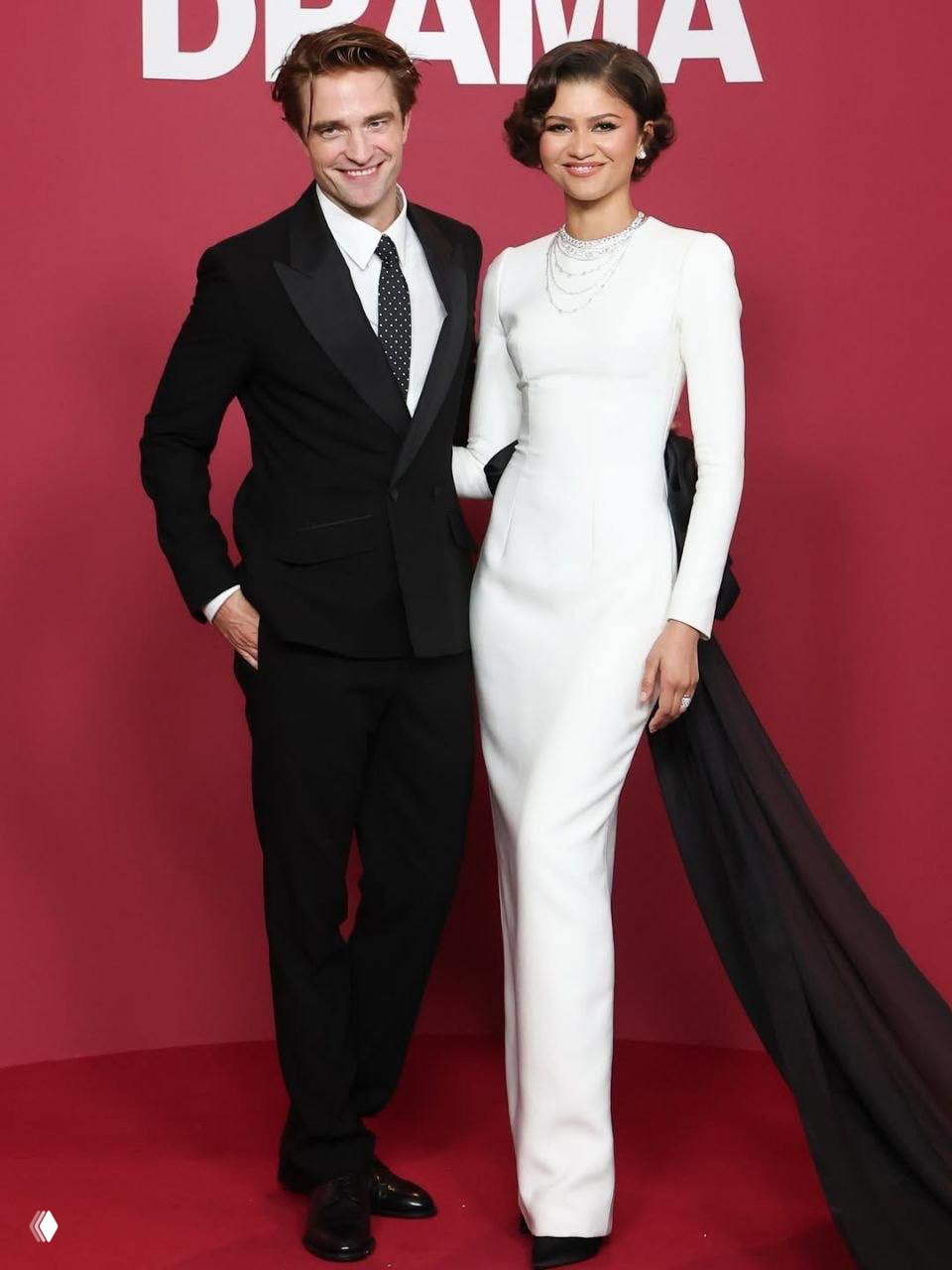 Совместный портрет актёра и актрисы в вечерних образах на красной дорожке на фоне баннера премьеры фильма в Париже, полный рост.