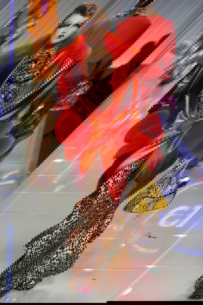 Алая атласная накидка с объёмным меховым воротником и леопардовой юбкой — роскошный вечерний образ из коллекции Dior 2004 на подиуме.