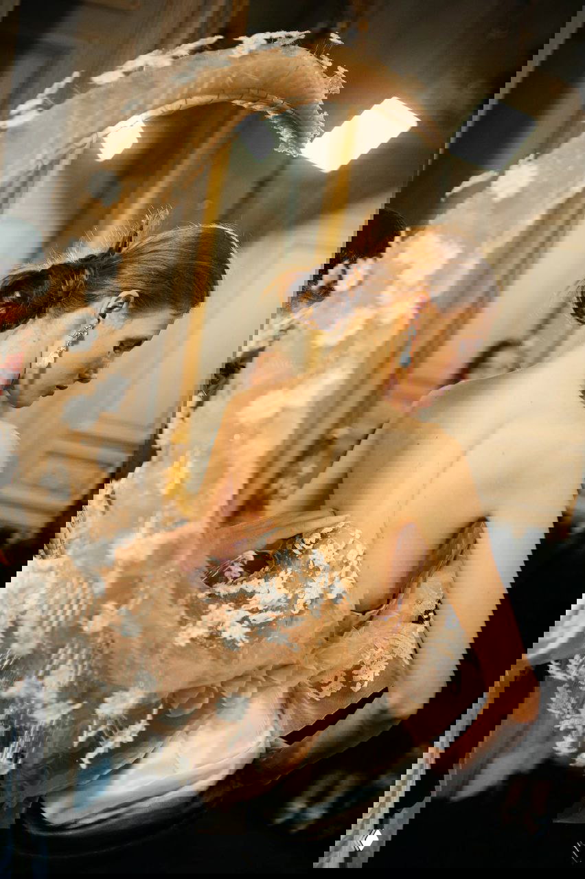 Крупный план модели в прозрачном корсете с объемной юбкой и ажурной отделкой, подготовка образа в бэкстейдже показа Schiaparelli.