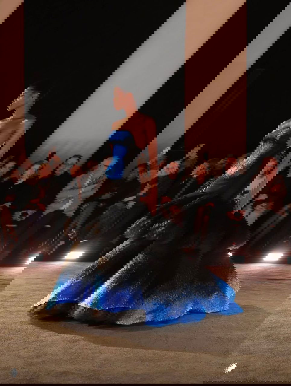 Модель в черном платье с градиентной голубой нижней частью и многослойной юбкой, драматичный силуэт на подиуме Schiaparelli.