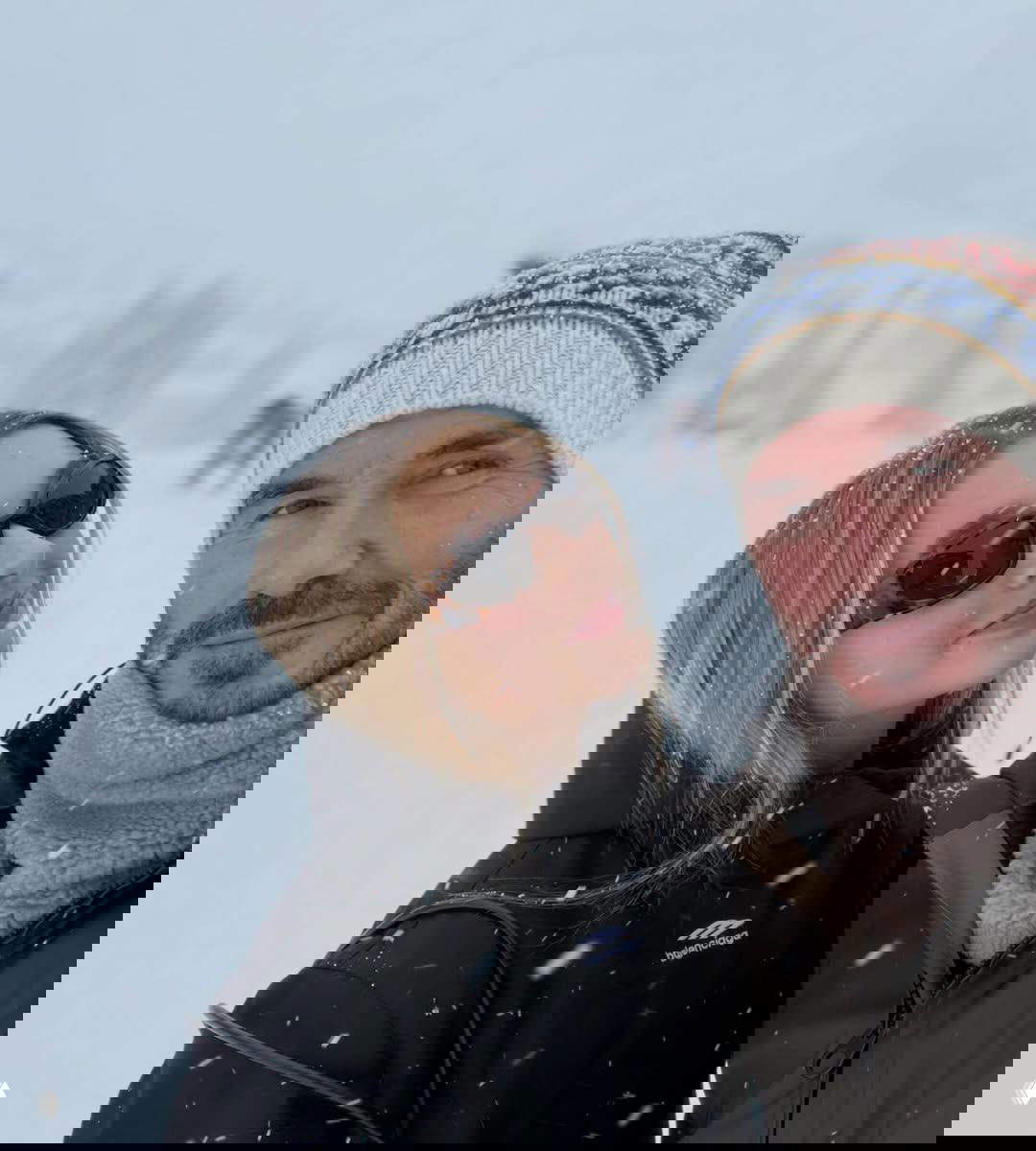 Снегопад в горах: мужчина и девушка в тёплой зимней одежде на улице Куршавеля, девушка в солнцезащитных очках.