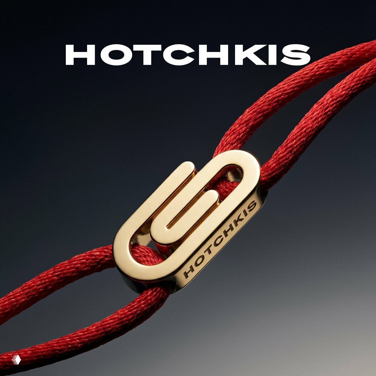 Золотая фурнитура Hotchkis на красном шнуре — детальный кадр замка с логотипом бренда, рекламная съёмка и ювелирная отделка