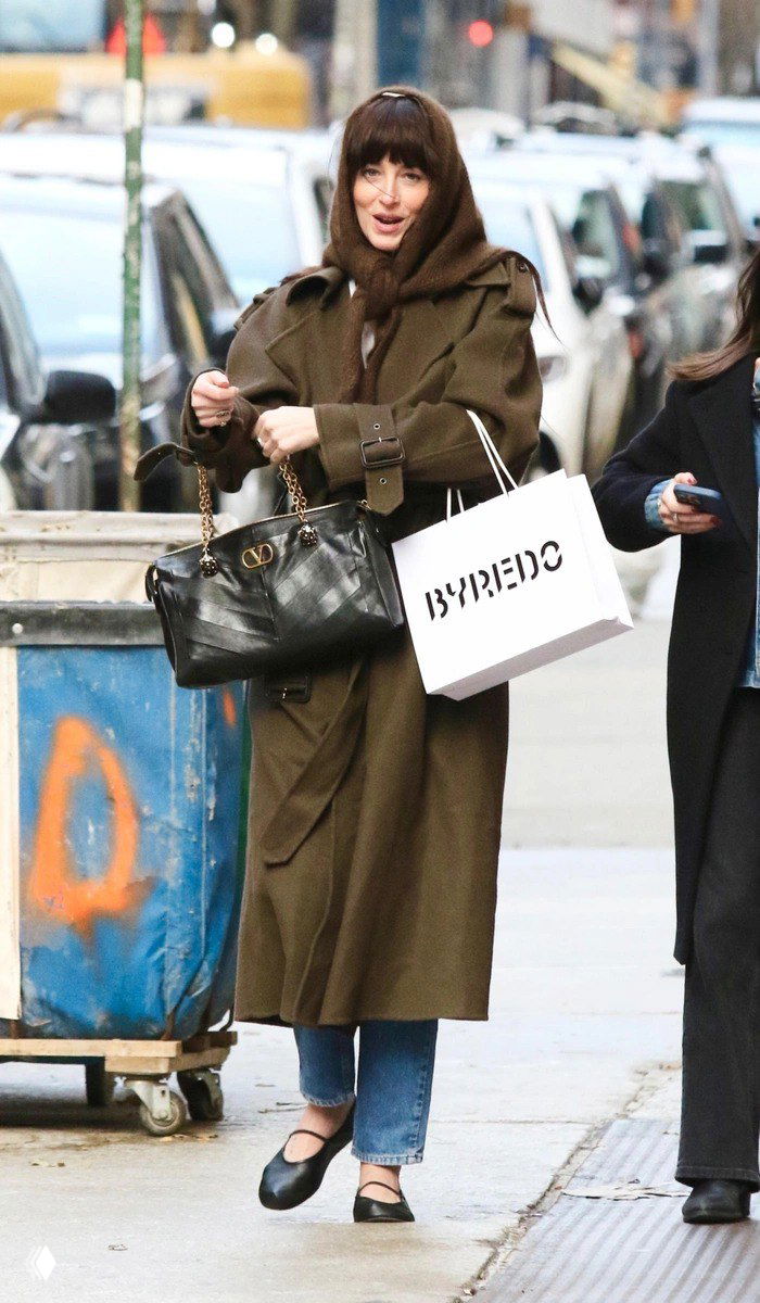 Уличный кадр: женщина в пальто несёт чёрную сумку Valentino Panthea с золотой цепочкой; сумка выглядит объёмной и подходит к повседневному городскому образу, сочетая люксовую фурнитуру и практичность.