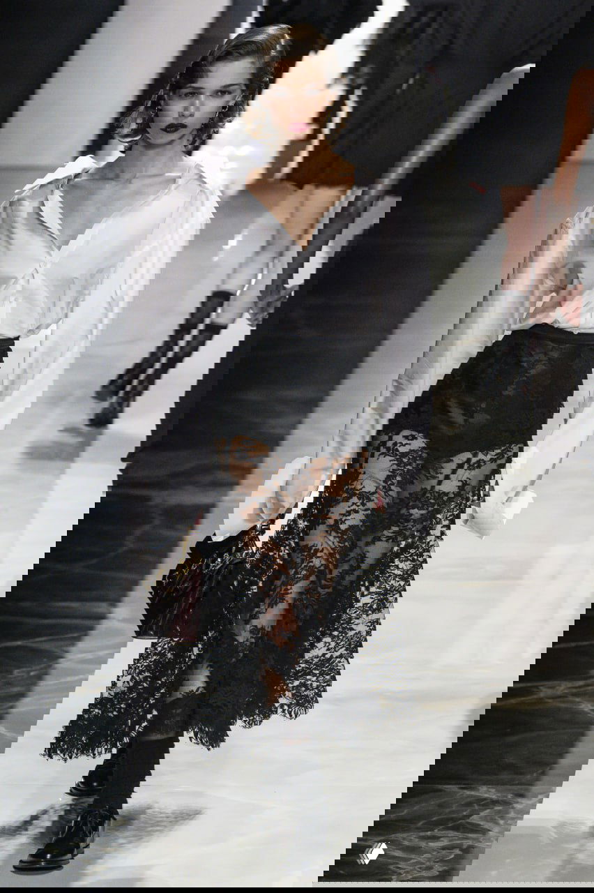 Образ: белая большая рубашка и чёрная кружевная юбка — сочетание контрастов, запечатлённое на показе Dolce & Gabbana 2026/27.