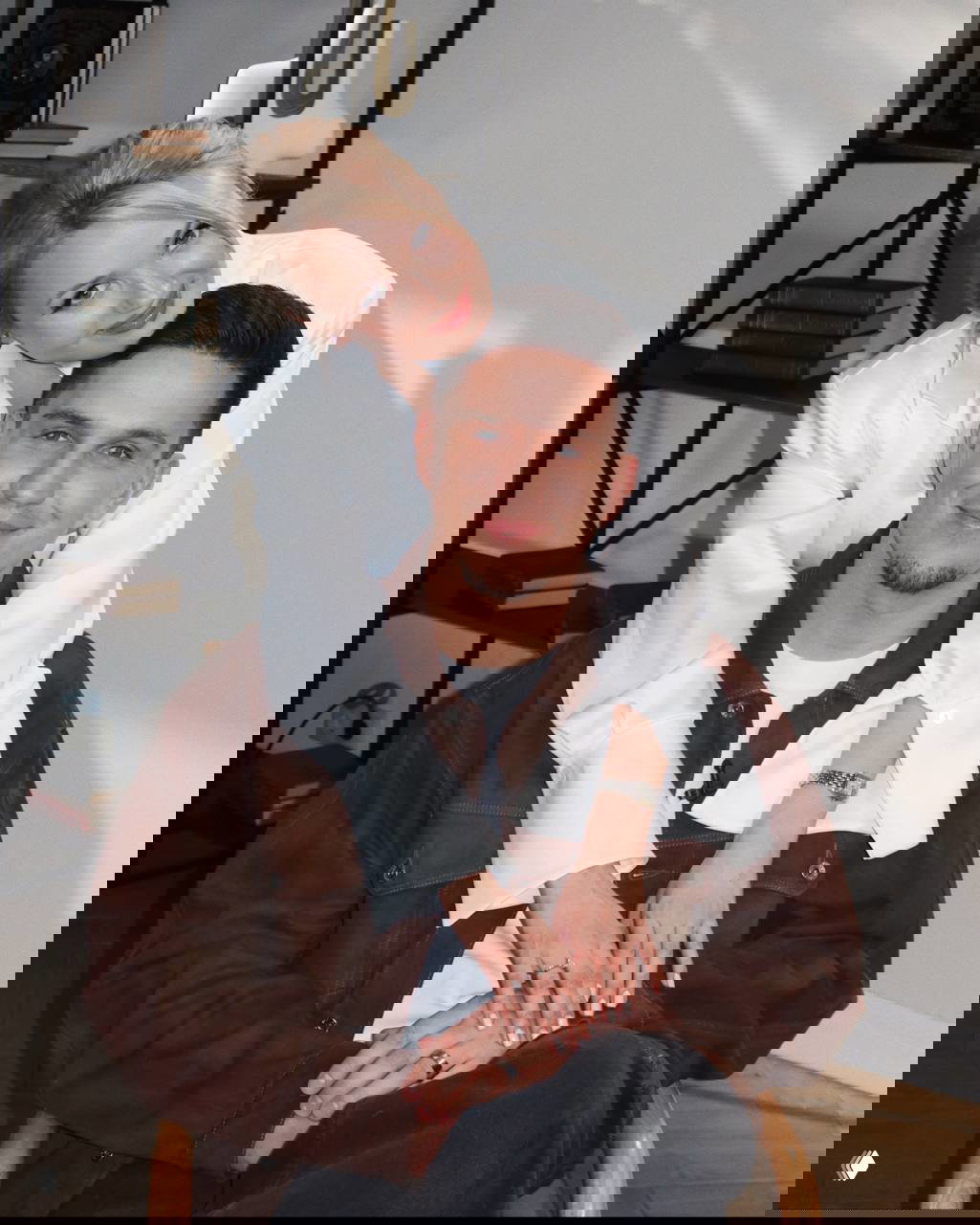 Двое улыбающихся людей позируют в интерьерной студии: женщина обнимает мужчину за плечи, тёплый портретный кадр для светской хроники.