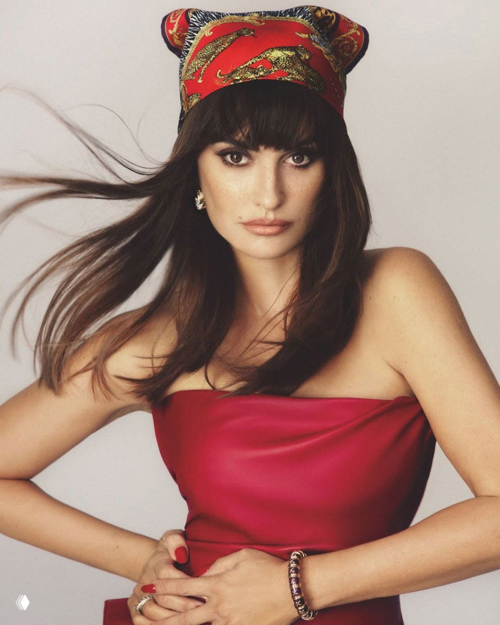 Крупный портрет женщины в платке на голове: развевающиеся волосы, лёгкий макияж и выразительный взгляд — кадр из журнальной студийной фотосессии