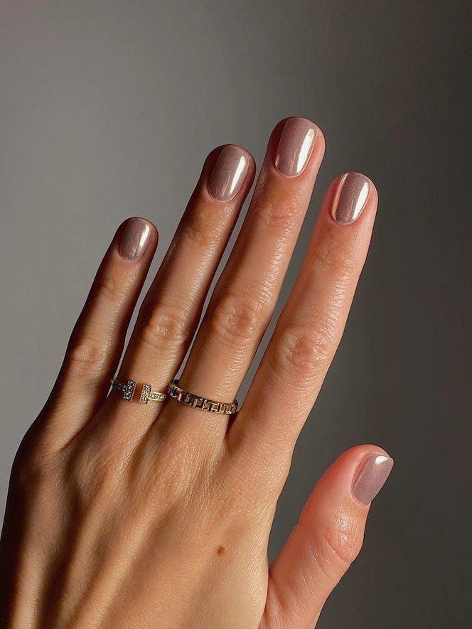 Длинные пальцы с коротким естественным маникюром в нюдово-коричневой полупрозрачной гамме и тонким блеском на поверхности — спокойный зимний дизайн.