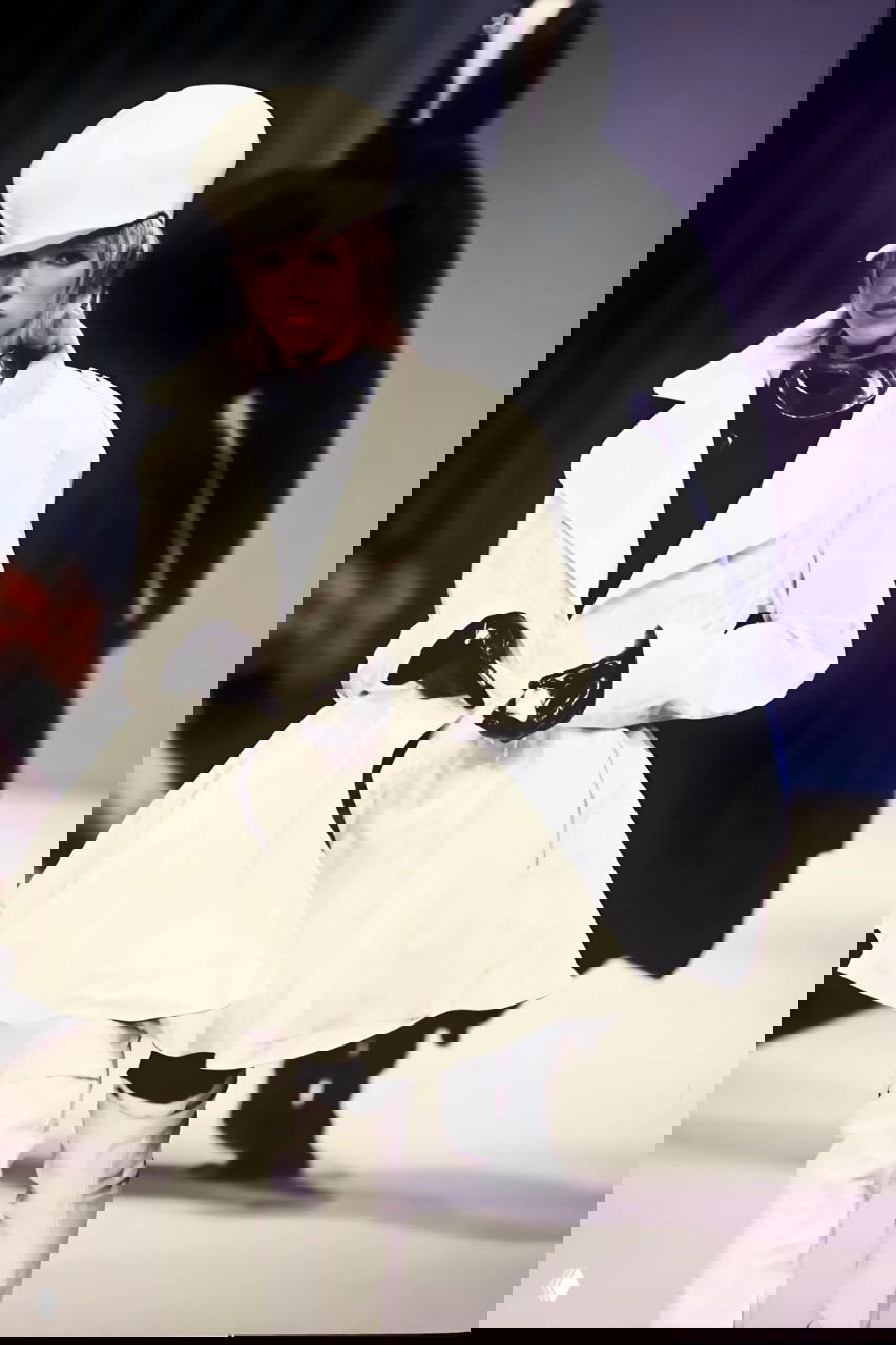 Модель в белом пышном пальто и высокой шляпе шагает по подиуму — контраст белого и чёрного в осенней коллекции Mugler 1990.