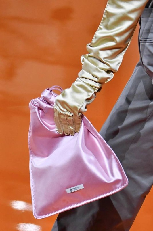 Розовый сатиновый мешочек Prada в руках модели, акцент на блеске и текстуре маленькой сумочки в вечернем и кэжуал луках.