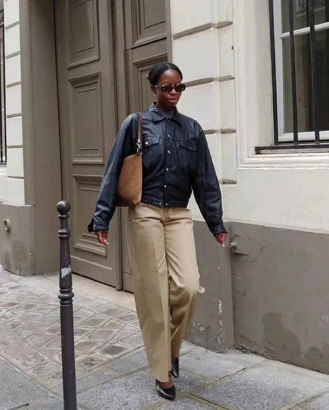 Городской стритстайл: модель в бежевых широких брюках и тёмной кожаной куртке, элегантный спокойный силуэт для любого дня.