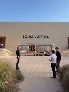 Небольшая сцена у фасада с логотипом Louis Vuitton и трейлером на песке; за кулисами — подготовка и элементы инсталляции, создающие пляжную атмосферу.