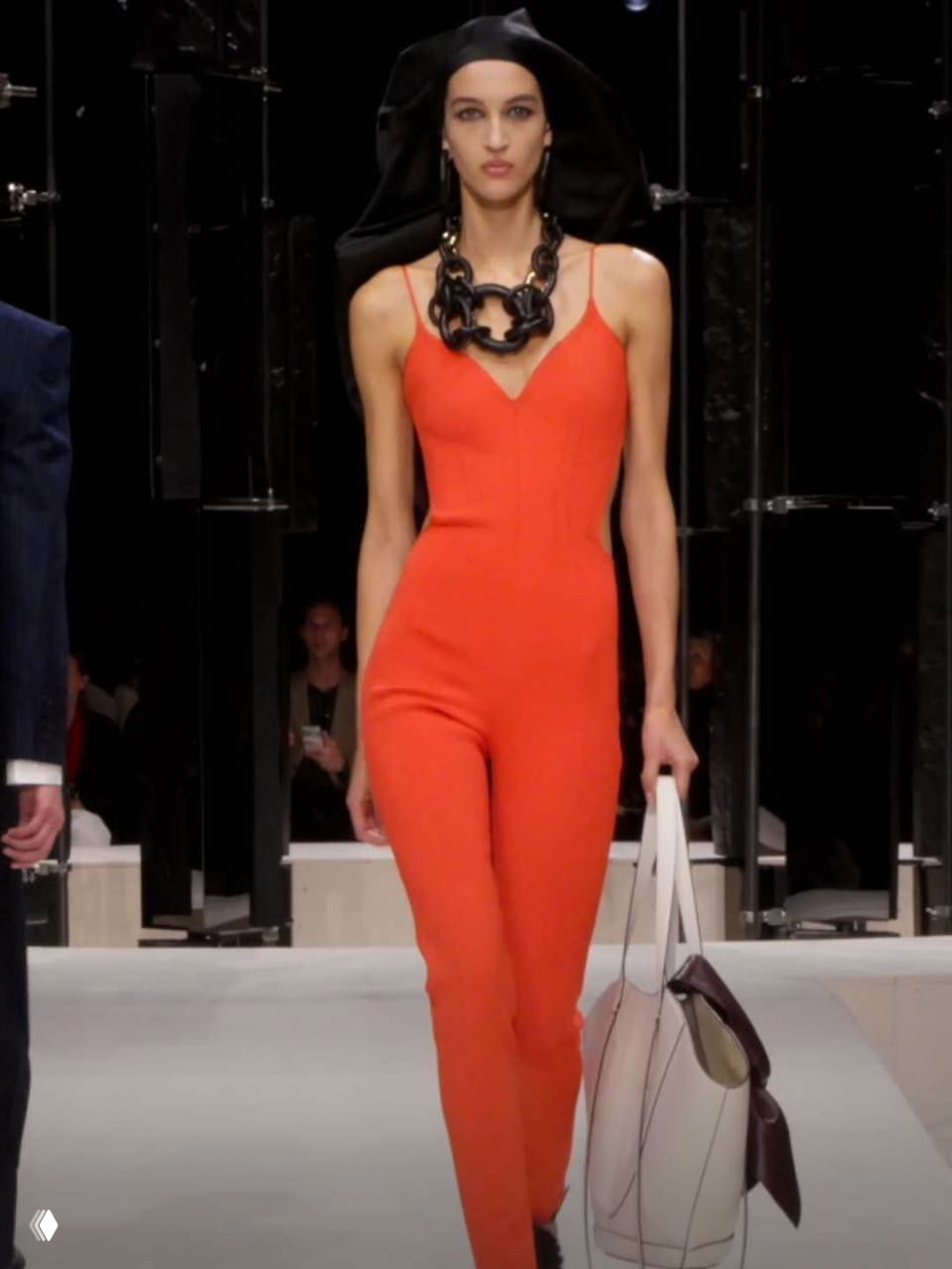 Оранжевый облегающий комбинезон на подиуме Givenchy: минималистичный крой, крупное ожерелье и сумка — съемка с показа. Фото Marie Claire.