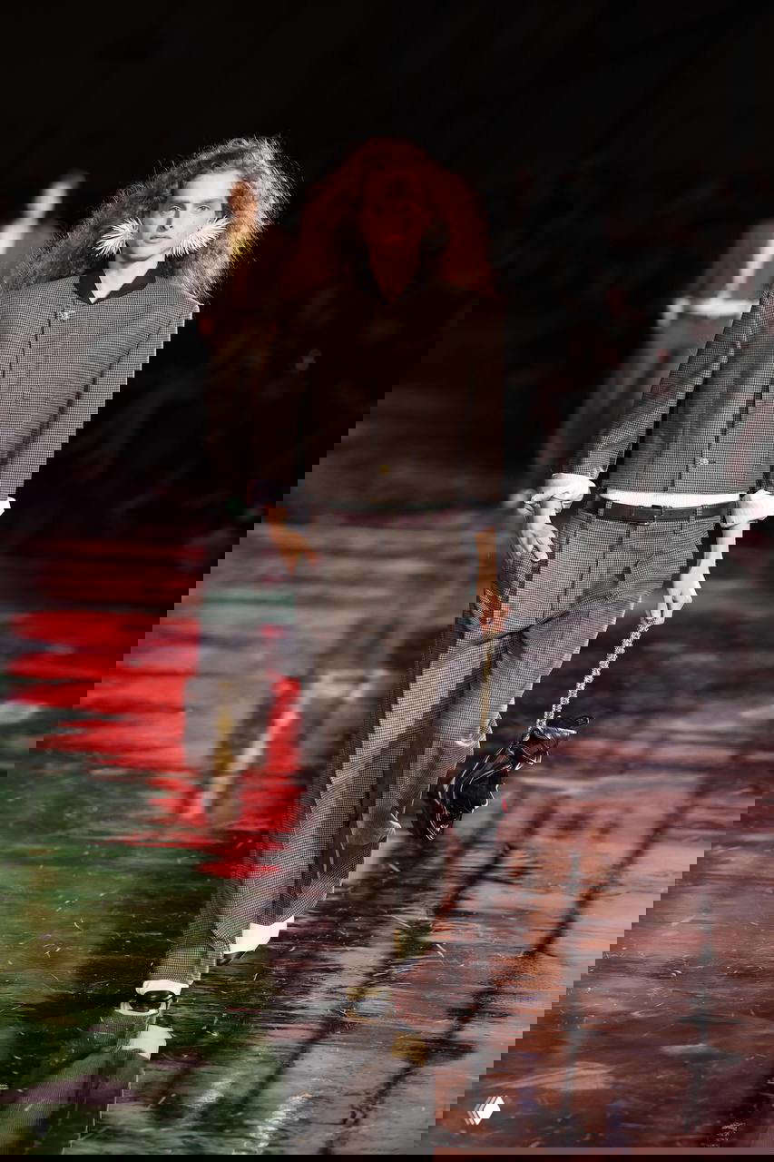 Модель в свободном костюме на глянцевом подиуме; сочетание мешковатых брюк и заниженной линии талии формирует новую пропорцию.