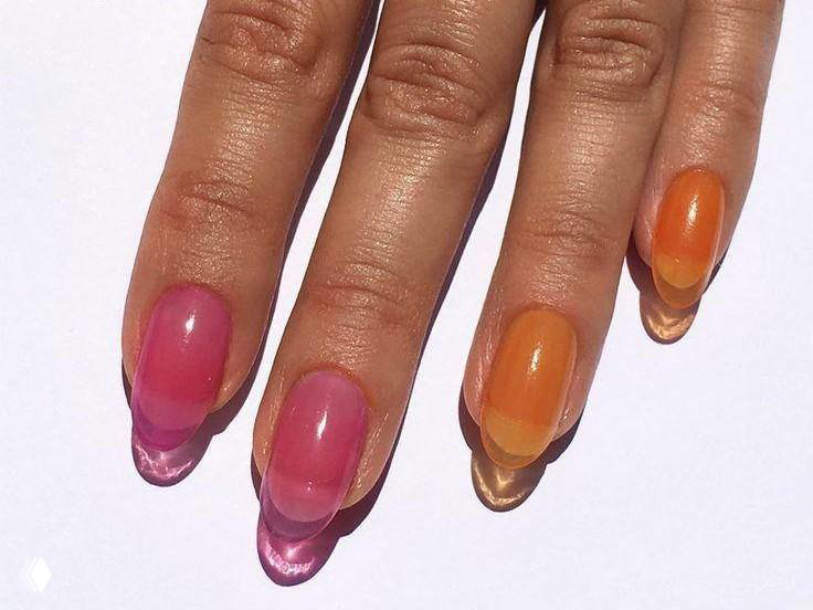 Руки с ярким градиентом прозрачных оранжево-розовых «стеклянных» типсами; видно игру света и объёмный эффект геля на кончиках.