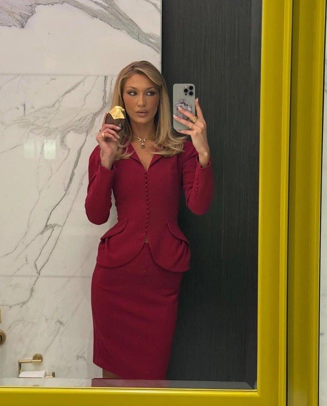 Селфи женщины в зеркале в красном костюме с приталенным пиджаком и юбкой-карандашем, образ в духе гламура и высокой женственности