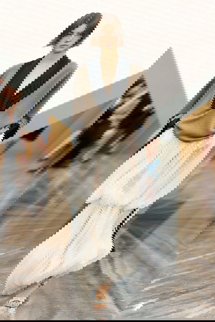 Снимок с подиума коллекции Dior весна‑лето 2026: свободный коричневый верх и пышная белая юбка из лёгкой ткани в движении.