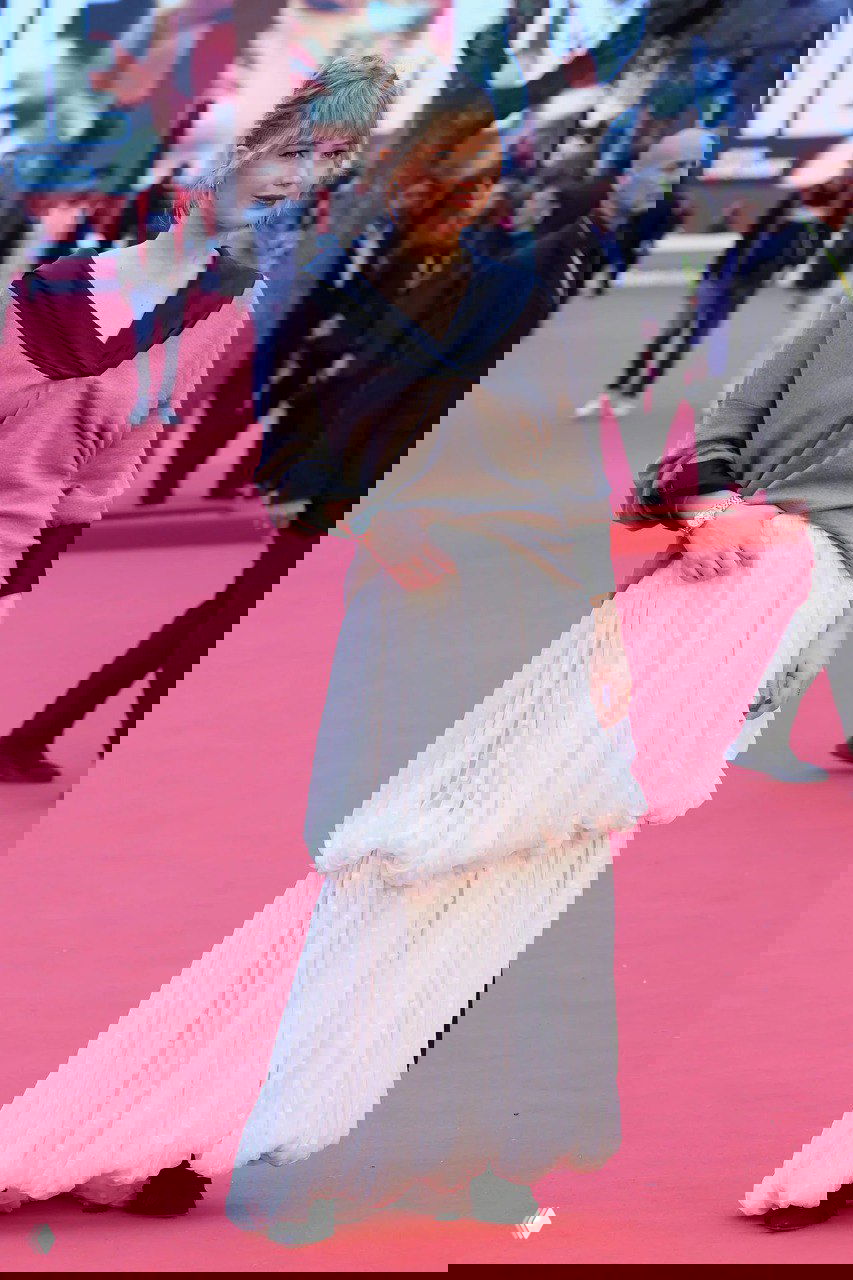 Полноразмерный кадр на фестивале: длинная белая многослойная юбка в сочетании с коричневым свободным свитером и чёрными деталями обуви.