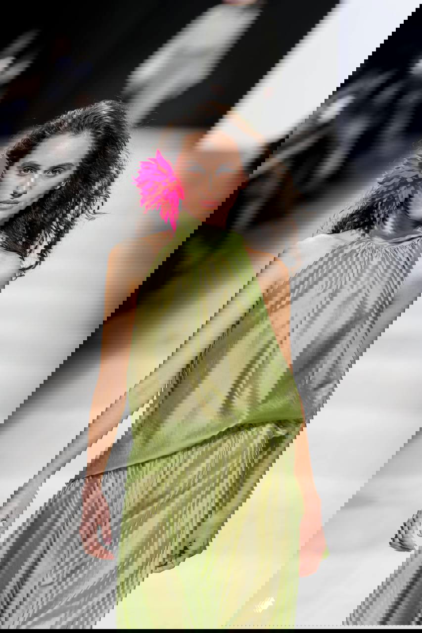 Модель в светло-зеленом шелковом платье с цветочным акцентом у уха — цвет «зеленый» как заметный тренд сезона.