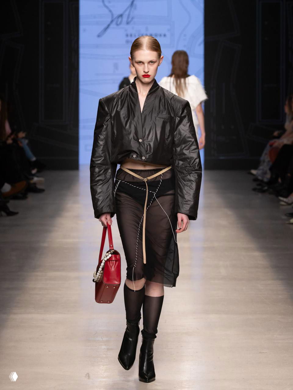 Черный укороченный бомбер в сочетании с прозрачной юбкой и декоративными ремнями — игра на прозрачности и базовой офисной детали.
