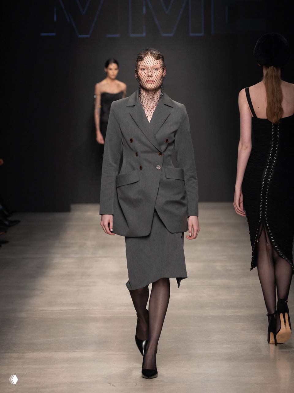 Серо-классический костюм с двубортным пиджаком и юбкой, строгий силуэт и плотные колготки — минимализм с отсылкой к 90‑м.