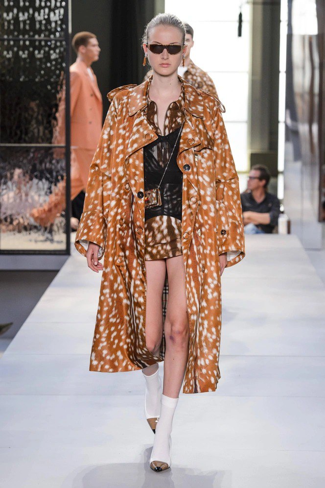 Модель на подиуме в длинном плаще и мини-платье с заметным пятнистым принтом 'Бэмби'; съёмка показа высшей моды и стилизованный лук.