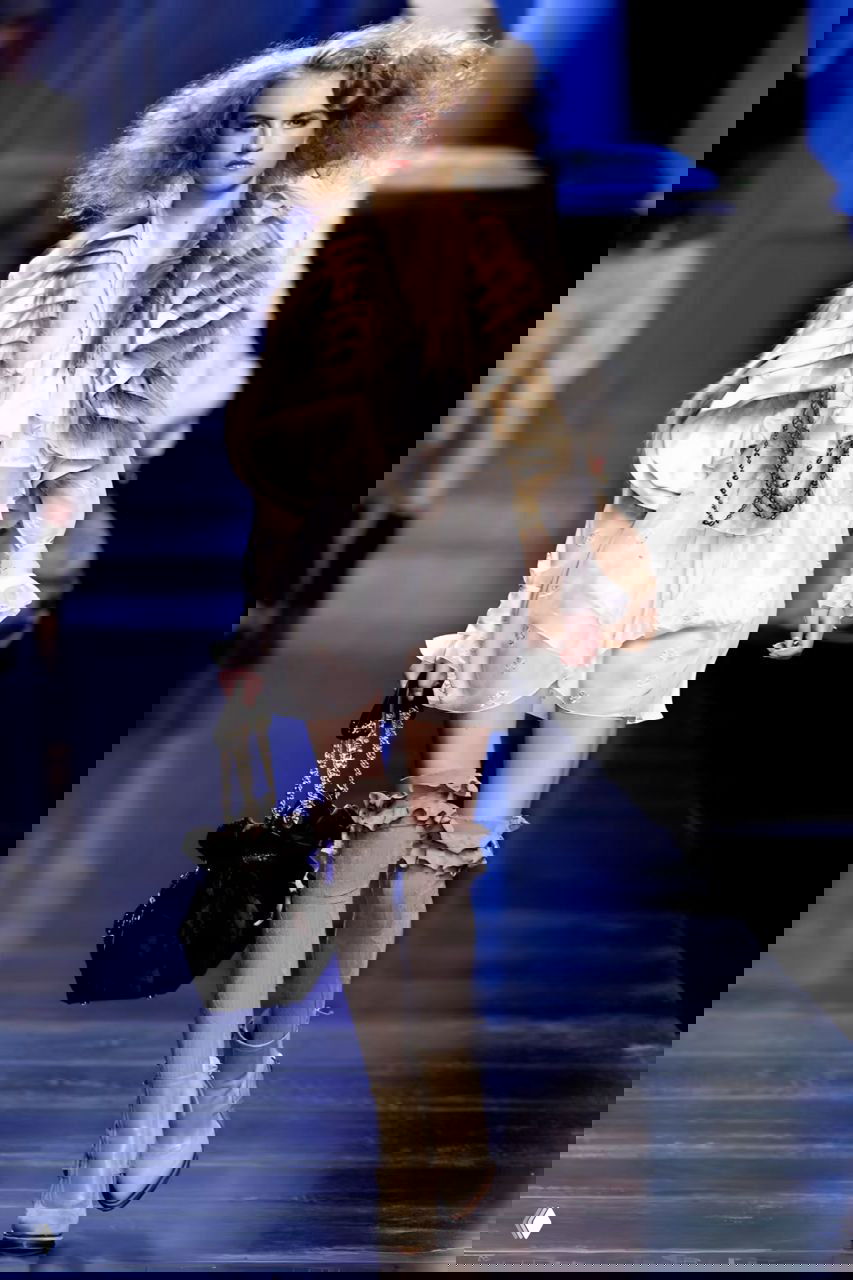 Модель в лёгком платье и многослойном воротнике из меха/ткани на подиуме Dior AW 2010 — акцент на фактурах и романтическом силуэте.