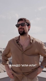 Мужчина в тёмных солнцезащитных очках и открытой рубашке на фоне городской набережной и неба; кадр из видео-интервью.