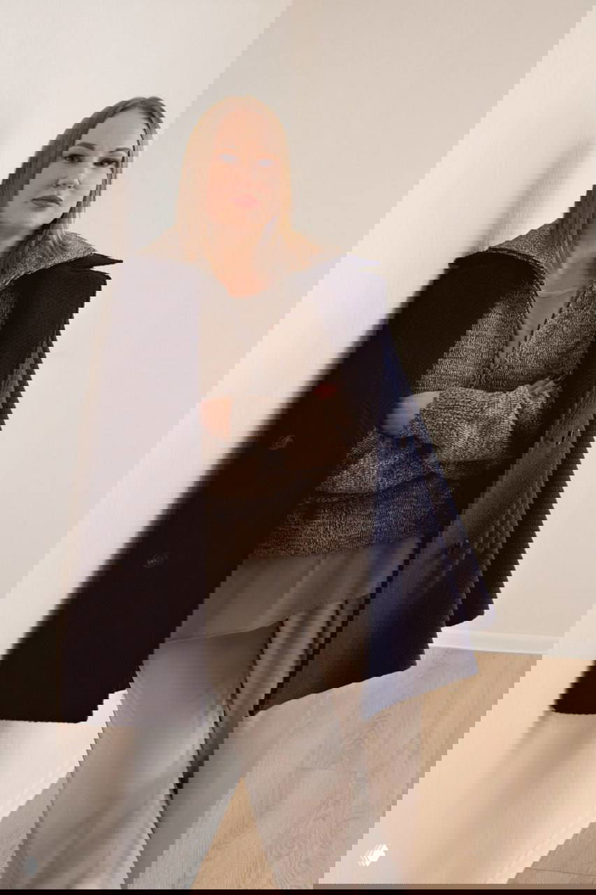 Портрет женщины в пальто у стены; интерьер стройки и детали строительной площадки видны позади, образ профессионала.