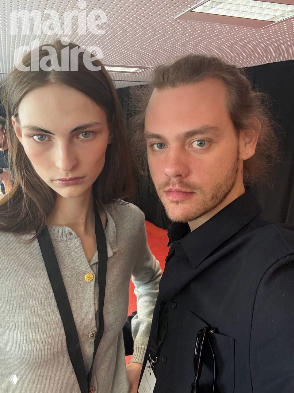 Селфи: модель в кардигане и мужчина с бейджем на фоне гримёрки — неформальный кадр из закулисья модной недели.