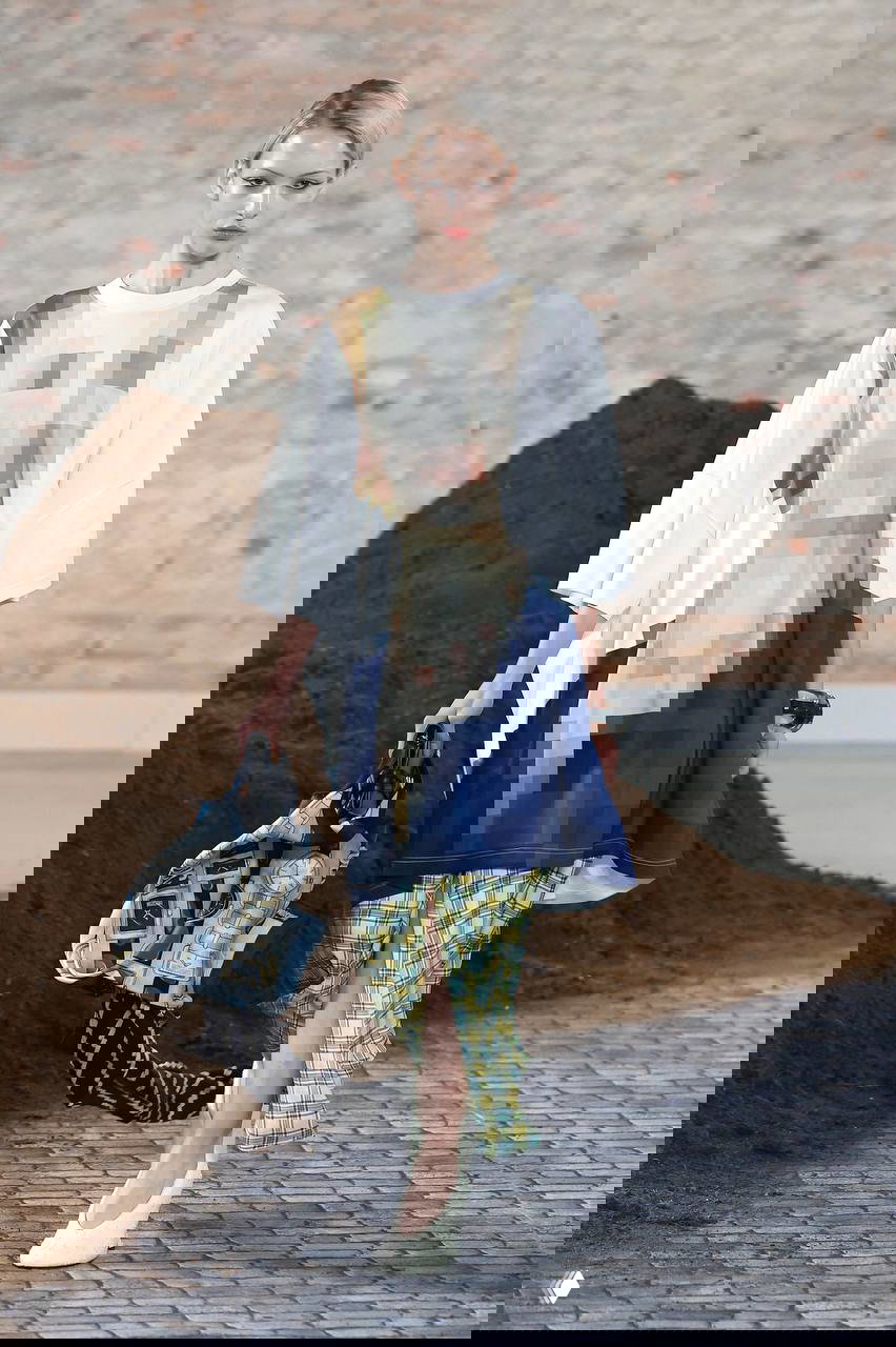 Модель в oversize‑топе с пикселизированным принтом и клетчатыми брюками — пример столкновения принтов и пэчворка в одном образе.