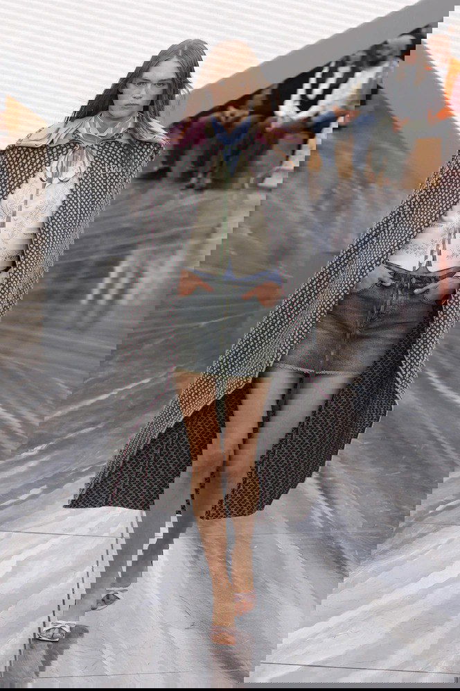 Модель в короткой джинсовой мини‑юбке и блузе, сочетание классического синего и светлых пастельных акцентов на подиуме коллекции.