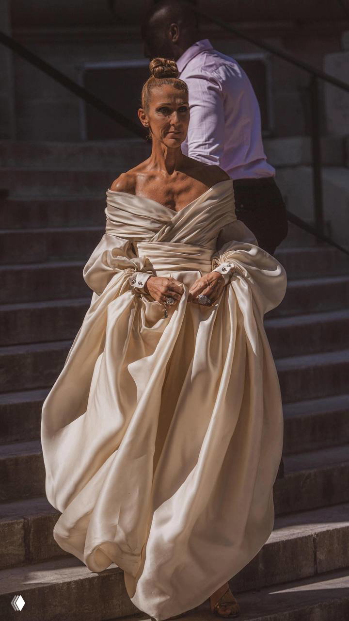 Селин Дион в роскошном объемном слоновой кости платье, спускается по ступеням — романтический, театральный образ haute couture.