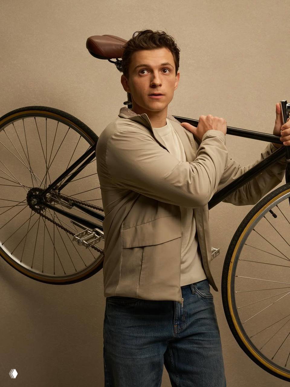Мужчина в светлой куртке держит велосипед на плече в студийной съёмке бренда спортивной одежды, подчёркнут минималистичный и утилитарный стиль.
