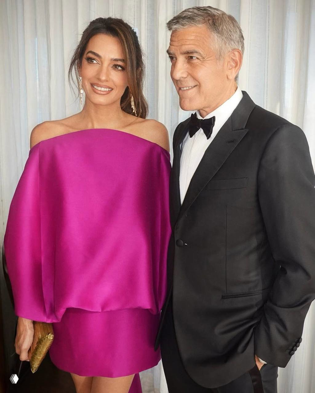 Портрет Джорджа и Амаль вблизи: она улыбается в насыщенном фуксии платье Balenciaga, он в чёрном костюме и бабочке.