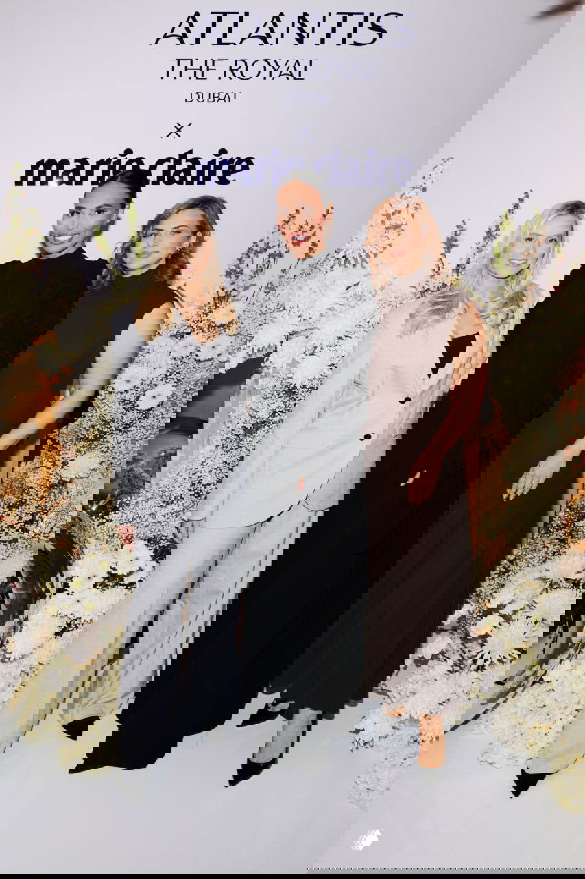 Три участницы события позируют у бренд-бэкдропа Atlantis The Royal x Marie Claire на фоне белых цветочных композиций и фирменного логотипа мероприятия.