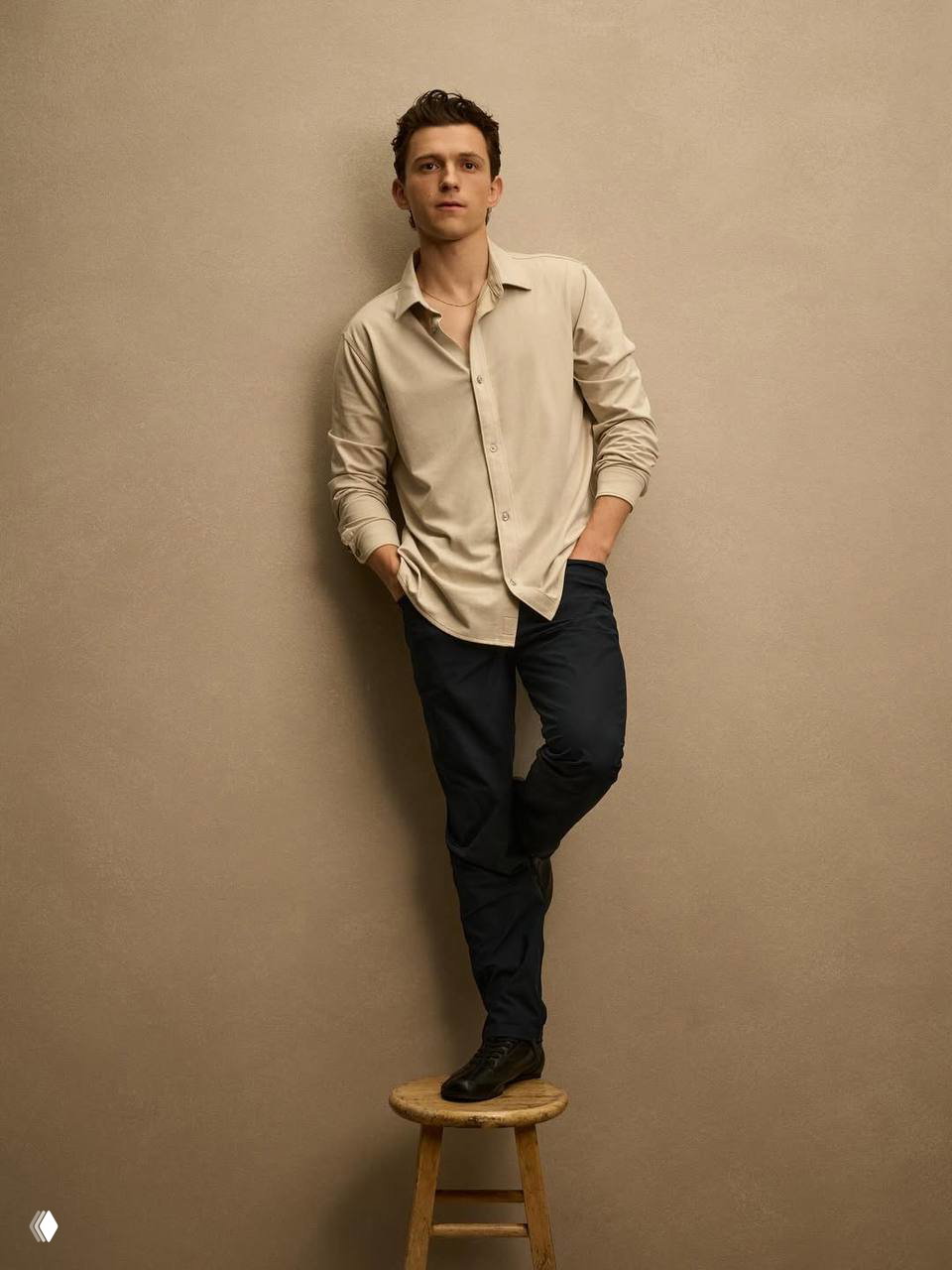 Полнофигураный портрет мужчины, опирающегося на табурет в студии, образ кампейна спортивной марки с минималистичным фоном и спокойной цветовой гаммой.