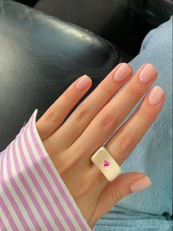 Рука с мягким нюдовым лаком на ровных коротких ногтях; на пальце крупное декоративное кольцо-печатка и полосатый рукав.