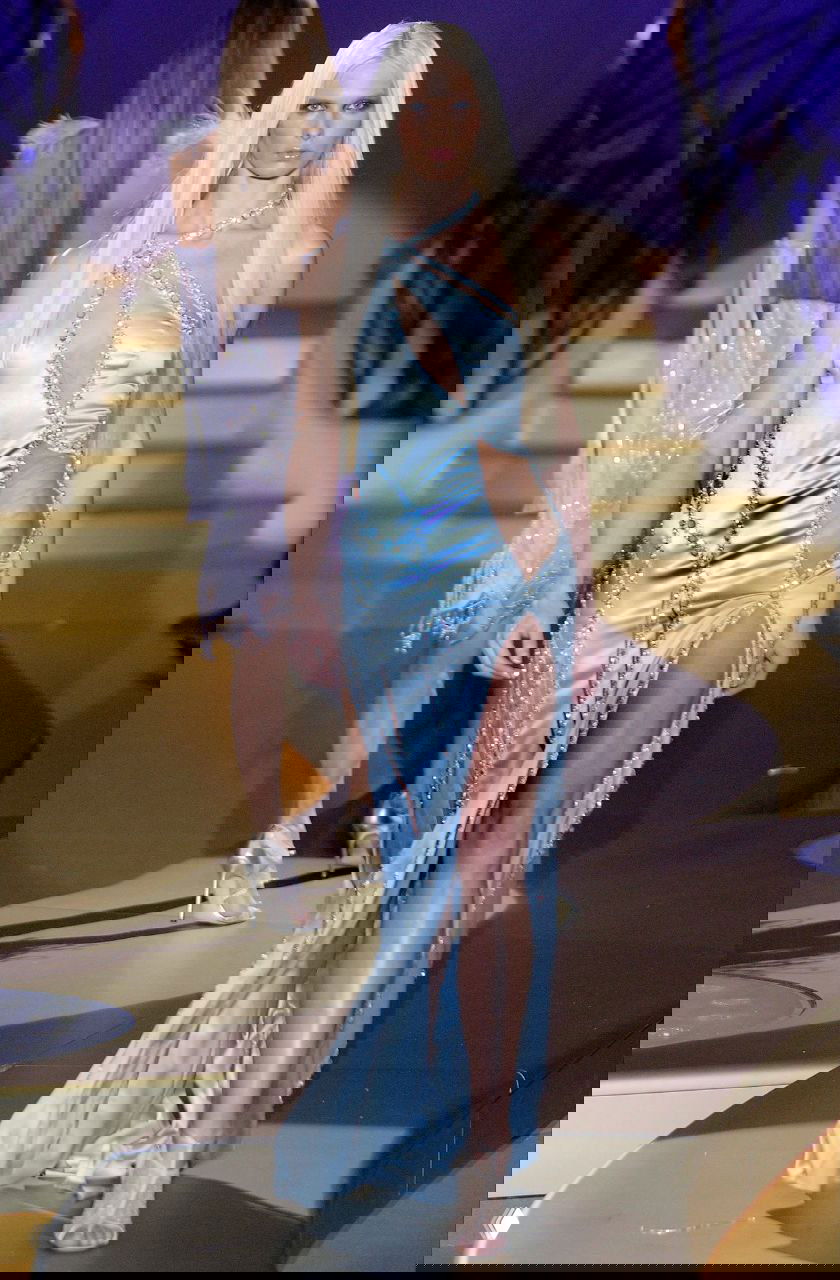 Высокая модель в голубом атласном платье с крупными вырезами и декором, эффектный вечерний образ из показа Versace 2004 на глянцевом золотом подиуме.