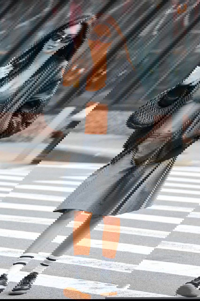 Уличный стритстайл с бомбером, укороченным топом и плиссированной юбкой, кроссовки и аксессуары, городской пейзаж на заднем плане