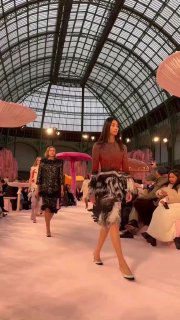 Две модели идут по подиуму Chanel среди гигантских грибов; внимание на кутюрные силуэты, фактуры и общую атмосферу сказочного леса