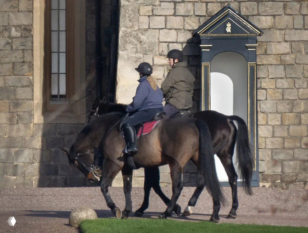 Принц Эндрю и его помощница верхом на лошадях у каменной стены Виндзорского замка, видна дежурная будка, снято папарацци.